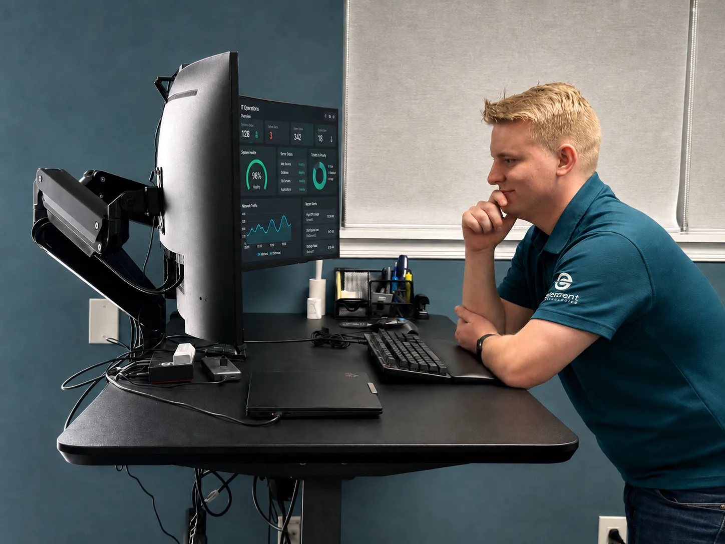 A 3rd Element technician reviewing an IT operations dashboard at a standing workstation